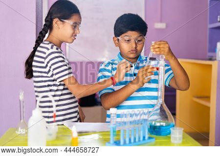 Close Up Shot Of Concentreted Kids Checking Or Analysing Chimical By Holding Flask While Doing Exper