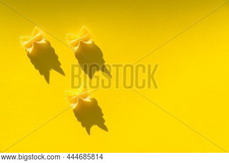 Three Pieces Of Farfalle Paste On A Yellow Background