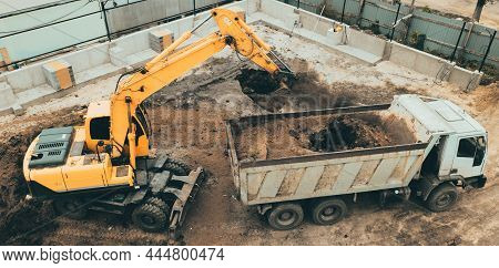 Excavator Digs Pit Foundation. Earthwork In Excavation In Construction Site, Aerial Top View.