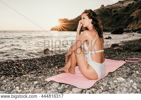 Middle Aged Well Looking Woman In White Swimsuit And Boho Style Braclets Practicing Outdoors On Yoga