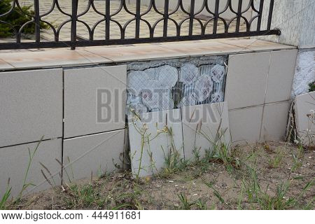 Ceramic Tiles Fall Off Concrete Fence Footing Outdoors. A Close-up Of A Wrought Iron Fence With Conc