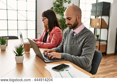 Two hispanic business workers with serious expressios working at the office.