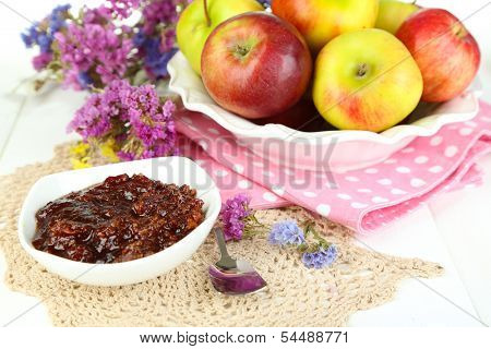 Juicy apples on plate on white wooden table