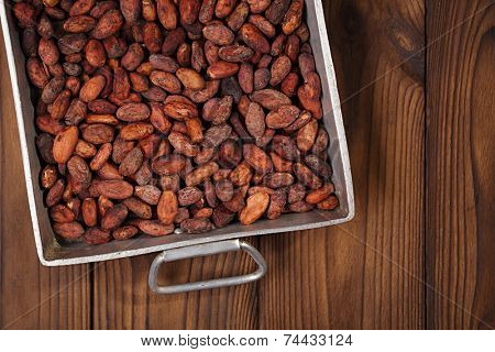 roasted cocoa chocolate beans in Vintage heavy cast aluminum roasting pan on wood background