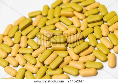 Piles Of Yellow And Orange Multi-vitamin Tablets Isolated