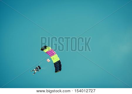 silhouettes of unidentified skydivers parachutist on blue sky on sunset