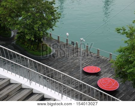 TWO RED CHAIRS ON WOODEN DECK BY THE RIVER