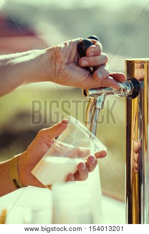 close-up of barman hand at beer tap pouring a draught lager beer