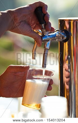 close-up of barman hand at beer tap pouring a draught lager beer