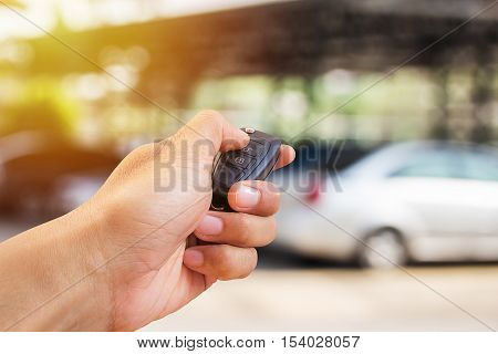 Men's hand presses on the remote control car alarm systems with sunlight