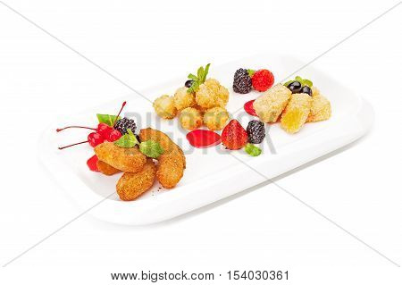 The meat balls and cheese sticks fried in breadcrumbs and served on a white dish, with strawberry, blackberry, bilberry, leaves of mint with cocktail cherries, isolated on a white background.