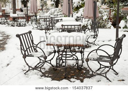 iron table and chairs covered with snow near the cafe