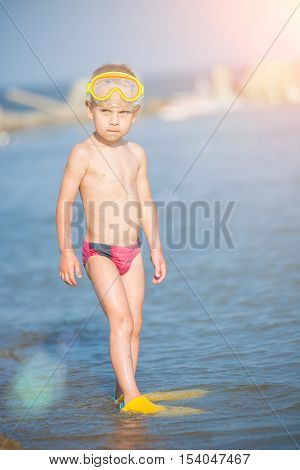 Little boy with snorkel by the sea. Cute little kid wearing mask and flippers for diving at sand tropical beach. Ocean coast.