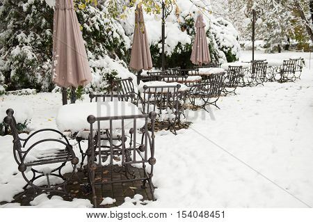 metal table and chairs covered with snow near restaurant