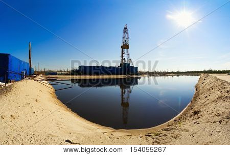 Drilling rig with reflection in the water. Siberia.