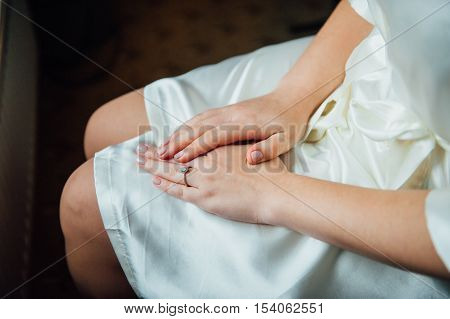 Tender beautiful bride's hands on elegant white dress closeup.