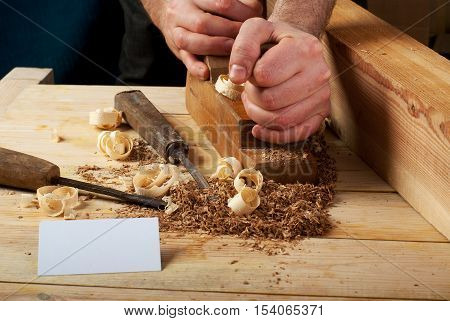 Blank business card on wooden table for carpenter tools with sawdust.Copy space. Top view.