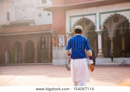 Delhi India - 2014 December 26 : The back of a young muslim boy walking in the courtyard of the fatehpuri mosque in the center of old Delhi India