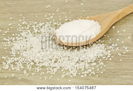 wooden spoon of coarse sea slat on a wooden textured background