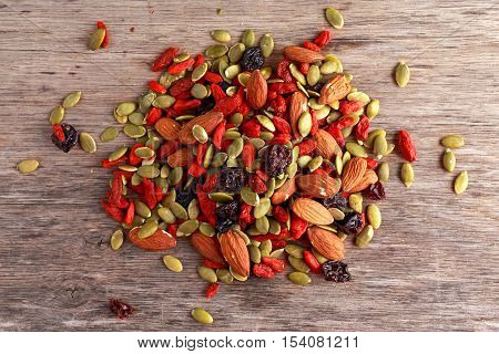 Nut mix snack with raisins, pumpkin seeds, almonds and goji berries on stone board.
