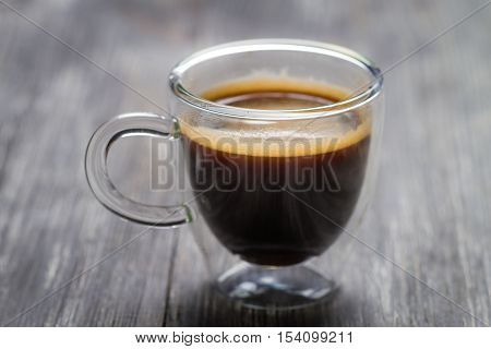 Closeup of small cup with espresso on old wooden table