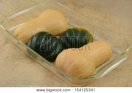Cooking preparation of raw Butternut and acorn squash halves in glass baking dish