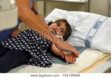 KAITAIA NZ - MAR 06: Little girl (Talya Ben-Ari age 3 ) during X-ray arm radiography on Mar 06 2014. The X-ray was discovered in 1895 in Germany.