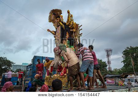 KOLKATA, INDIA - OCTOBER 10, 2016: Durga idol being brought down from a truck by group of workers for immersion in the Ganges river. The immersion marks the end of the five day long Durga puja.