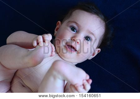 Baby On Her Back Holding Hands Over Legs