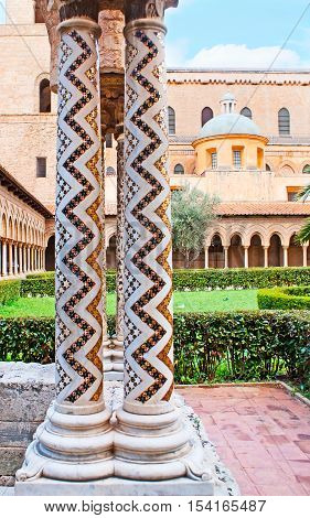 The white stone columns in garden of Monreale Cathedral decorated with zigzag inlay consisting of small mosaic stars Sicily Italy.