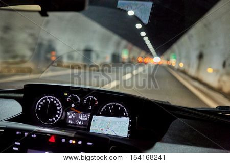 View through windscreen of car moving by road in tunnel.