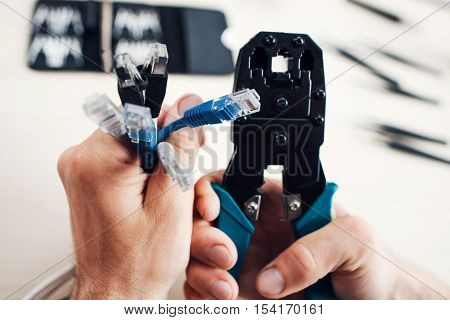 Hands holding rj45 cables and forceps for crimping modular plug. Network development, telecommunications, business concept