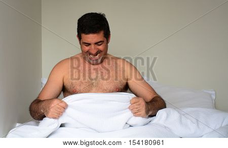 Happy Man In His Forties (40S) In Bed Looking Down At His Penis
