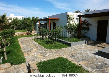 HERAKLION CRETE GREECE - MAY 13 2014: The blue sky modern building of villa with flowers and palms on the terrain of luxury class hotel on the Mediterranean coast of Crete May 13 2014 Greece.