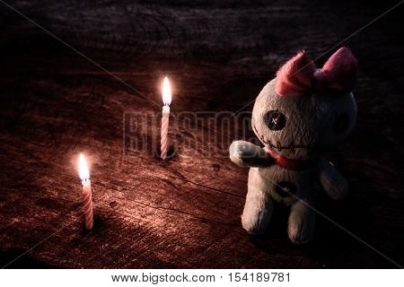 Vintage evil spooky doll with light of candle in darkness on wooden table halloween concept.