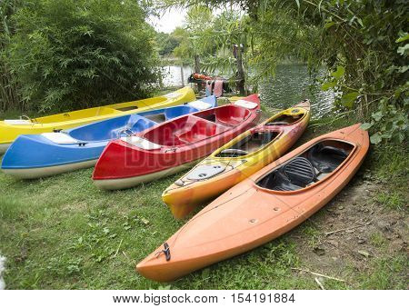 Several single and double kayaks on the riverside in cloudy day