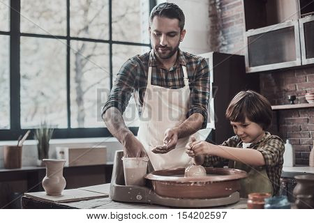 Pottery class. Confident young man and little boy making ceramic pot on the pottery class