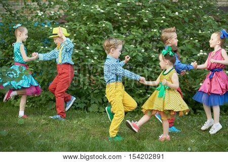 Three children couples dance on grassy lawn outdoor.