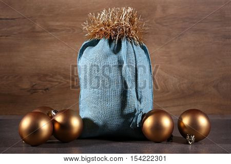 Soft blue Santa bag and  golden balls. Woven linen fabric pouch. Gifts bag in wooden background.
