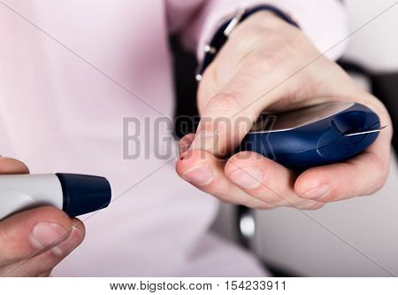 Dependent first type diabetes patient. Measuring glucose level blood test using ultra mini glucometer and small drop of blood from finger and test strips.