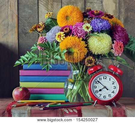 Back to school. September 1 knowledge Day teacher's Day. Still life with books bouquet and alarm clock.