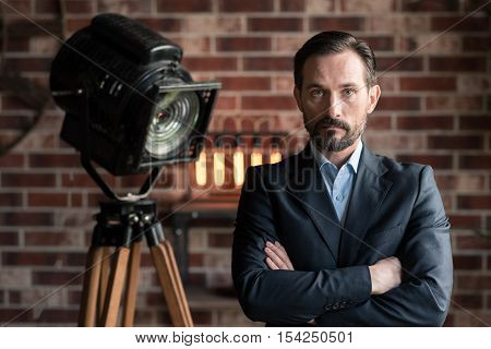 We need to talk. Handsome serious determined man standing against the wall and crossing his arms while looking at you