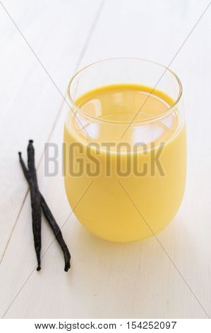 Vanilla milk in glass with vanilla pods selective focus vertical