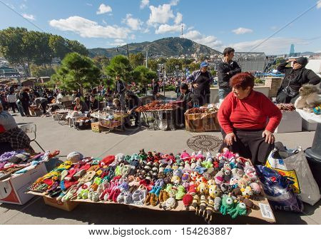 TBILISI, GEORGIA - OCT 16, 2016: Elderly woman selling handmade toys on outdoor market during city festival Tbilisoba on October 16, 2016. Tbilisoba is traditional festival in capital of Georgia from 1979