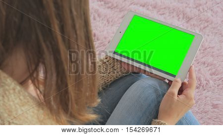 Woman looking at horizontal tablet computer with green screen. Close up shot of woman's hands with pad