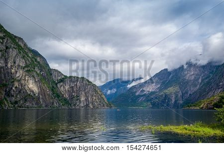 Scenic Norway fjord landscape with north sea shores, steep mountains and kayak on the water. Eidfjord, Hordaland, Norway