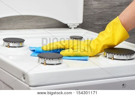 Hand In Yellow Glove Cleaning White Stove With Blue Rag
