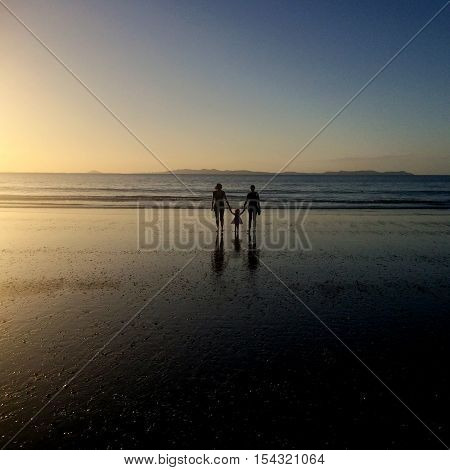 Grandmother Daugther and grandhild walks on the beach during summer holiday on sunset.