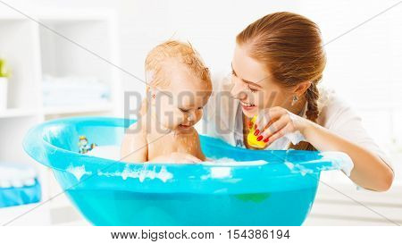 Happy family mother bathes the baby in a blue bath