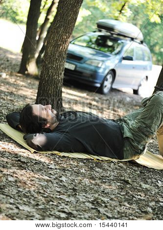 Man resting on ground beside his car
